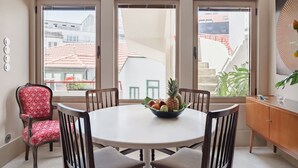 Un coin repas avec une table ronde, des chaises et un saladier de fruits.