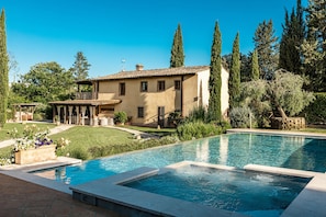 A swimming pool, a house, and surrounding greenery.