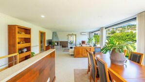 A spacious living area with a wooden dining table, a kitchen in the background, and a large window offering a view of greenery. - Old house Alembic in Ponte de Lima (Ponte de Lima)