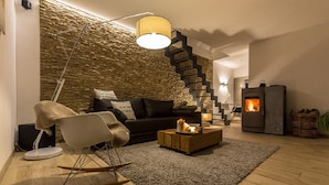 Een moderne woonkamer met een stenen muur, een zwarte trap, een open haard en een knus zithoekje.