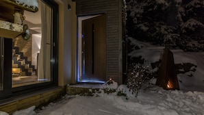 Een modern huis met een sneeuwbedekte ingang en een verlicht interieur.