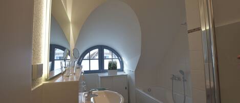 A bathroom with a large window, a sink, a bathtub, and a shower.