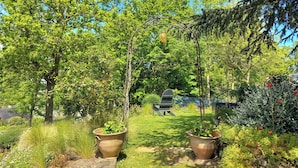A garden with a lawn, potted plants, and a wooden chair. - Quiet and seaside in charming house 3000 m2 park (Créhen)