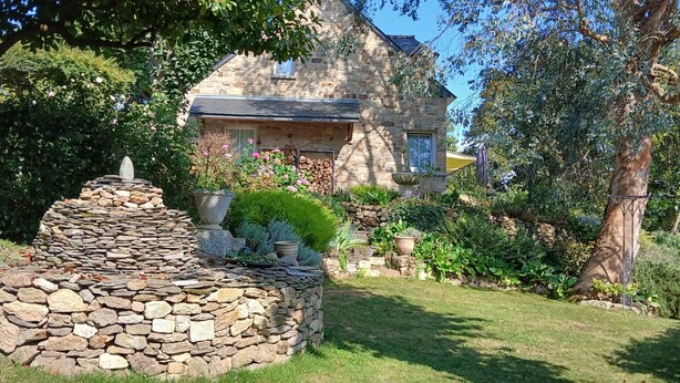 A stone fountain in a garden with a stone house in the background. - Quiet and seaside in charming house 3000 m2 park (Créhen)