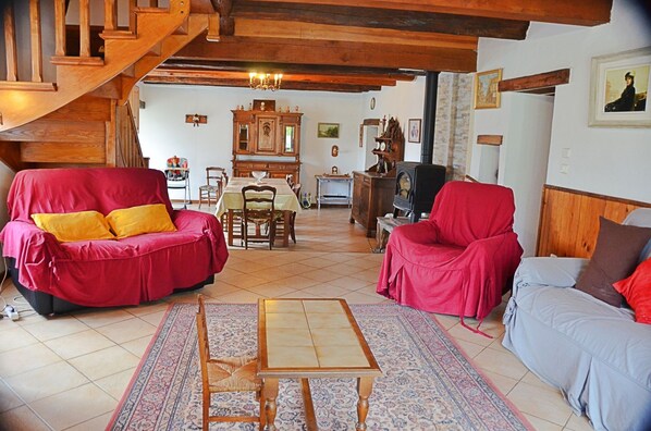 A cozy living room with a wooden staircase, a dining area, and a fireplace.