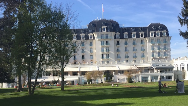 Un grand hôtel historique, doté d’un style architectural européen classique, avec de nombreux balcons et un drapeau bien visible.