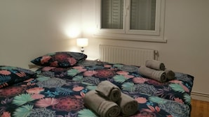 Une chambre à coucher avec un lit, une fenêtre avec des volets, un radiateur et une lampe.
