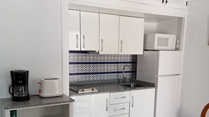 A compact kitchen with white cabinets, a microwave, a coffee maker, and a toaster. - Apartment by the pool (SAN MIGUEL DE SALINAS)