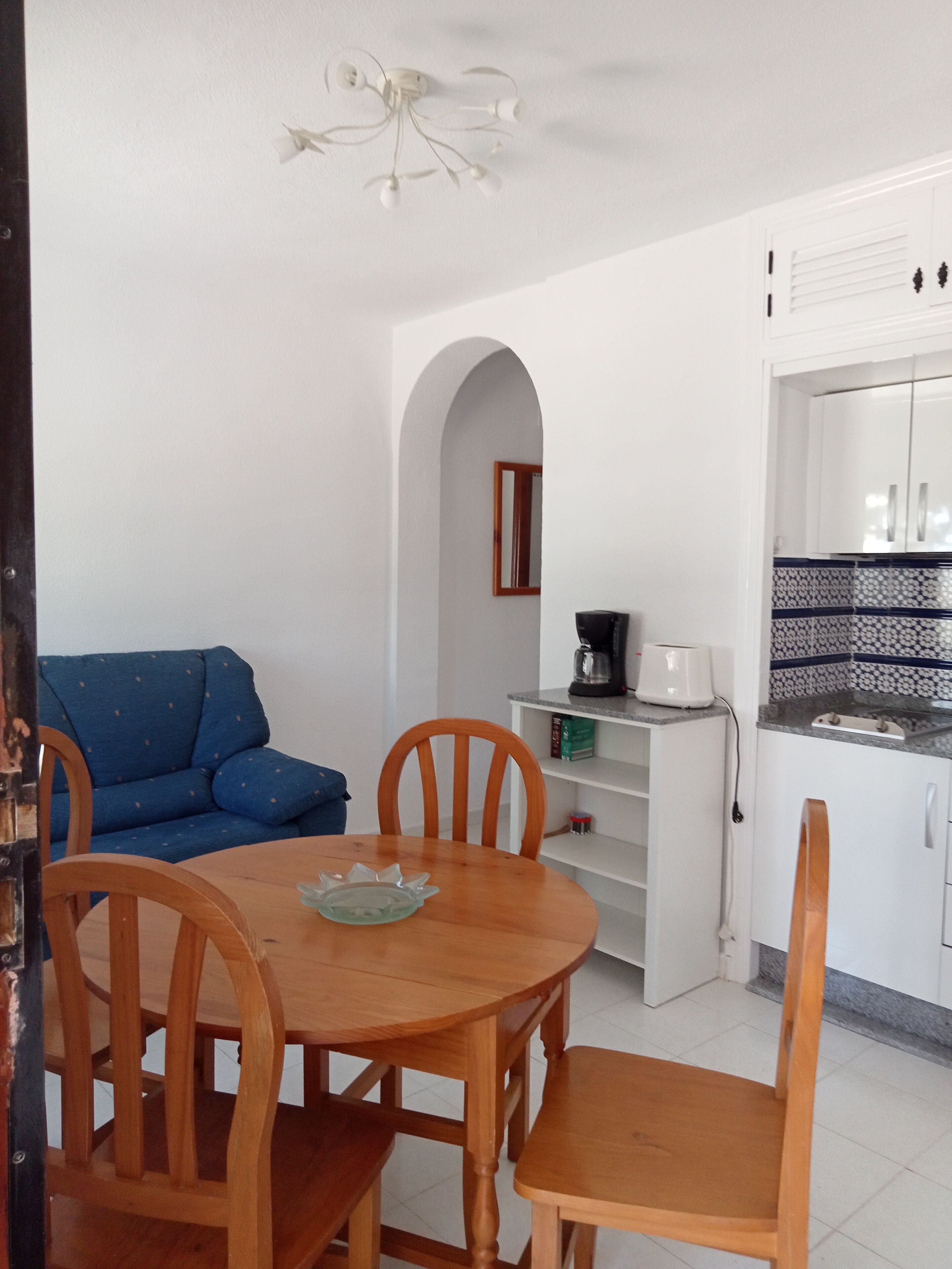 Um espaço compacto com área de refeições, cozinha compacta e sofá azul.