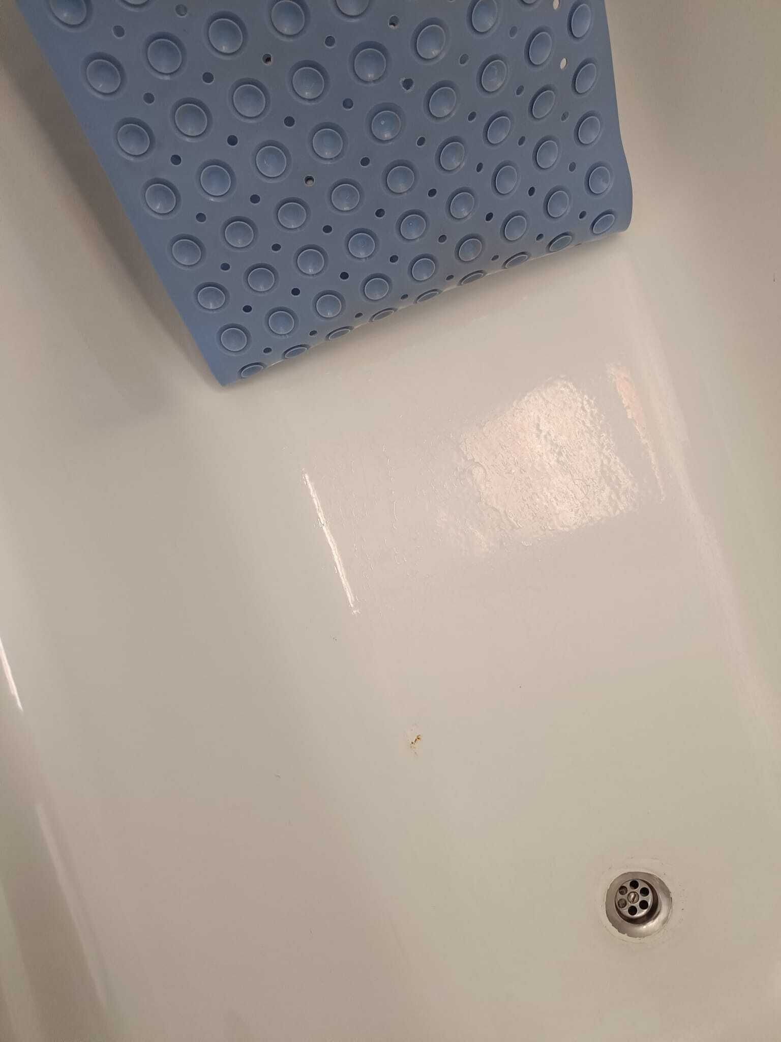 Une salle de bain avec un lavabo blanc, un tapis bleu à motifs et un drain.