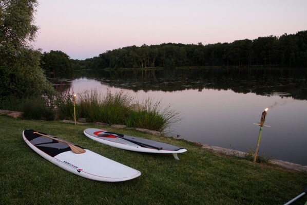 Due tavole da paddleboard su una riva erbosa di un lago.