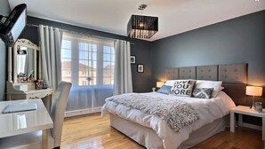 Un dormitorio moderno con una cama grande, un escritorio y una silla.