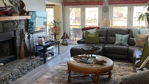 A spacious living room with a stone fireplace, a leather sofa, a coffee table, and a television. - Fantastic house, dock, water toys and hot tub!! Summer dates available!! (Catawba)