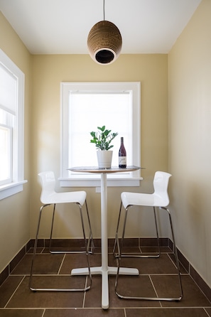 A small dining area with a white table, two white chairs, a potted plant, and a wine bottle. - ❤️ CLEAN COZY ★ BUNGALOW ★ NEAR DOWNTOWN (Portland)