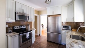 Una cocina moderna con gabinetes blancos, electrodomésticos de acero inoxidable y un salpicadero de azulejos.