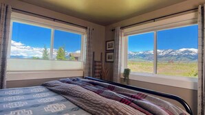 Quarto com cama, duas janelas e vista para as montanhas.