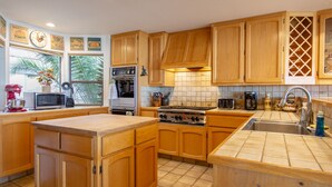 A kitchen with wooden cabinets, a stove, a microwave, and a sink.