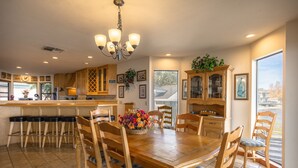 A spacious kitchen with a wooden dining table, bar stools, and a chandelier.