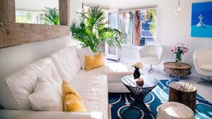A modern living room with a white sofa, a coffee table, and a large plant.