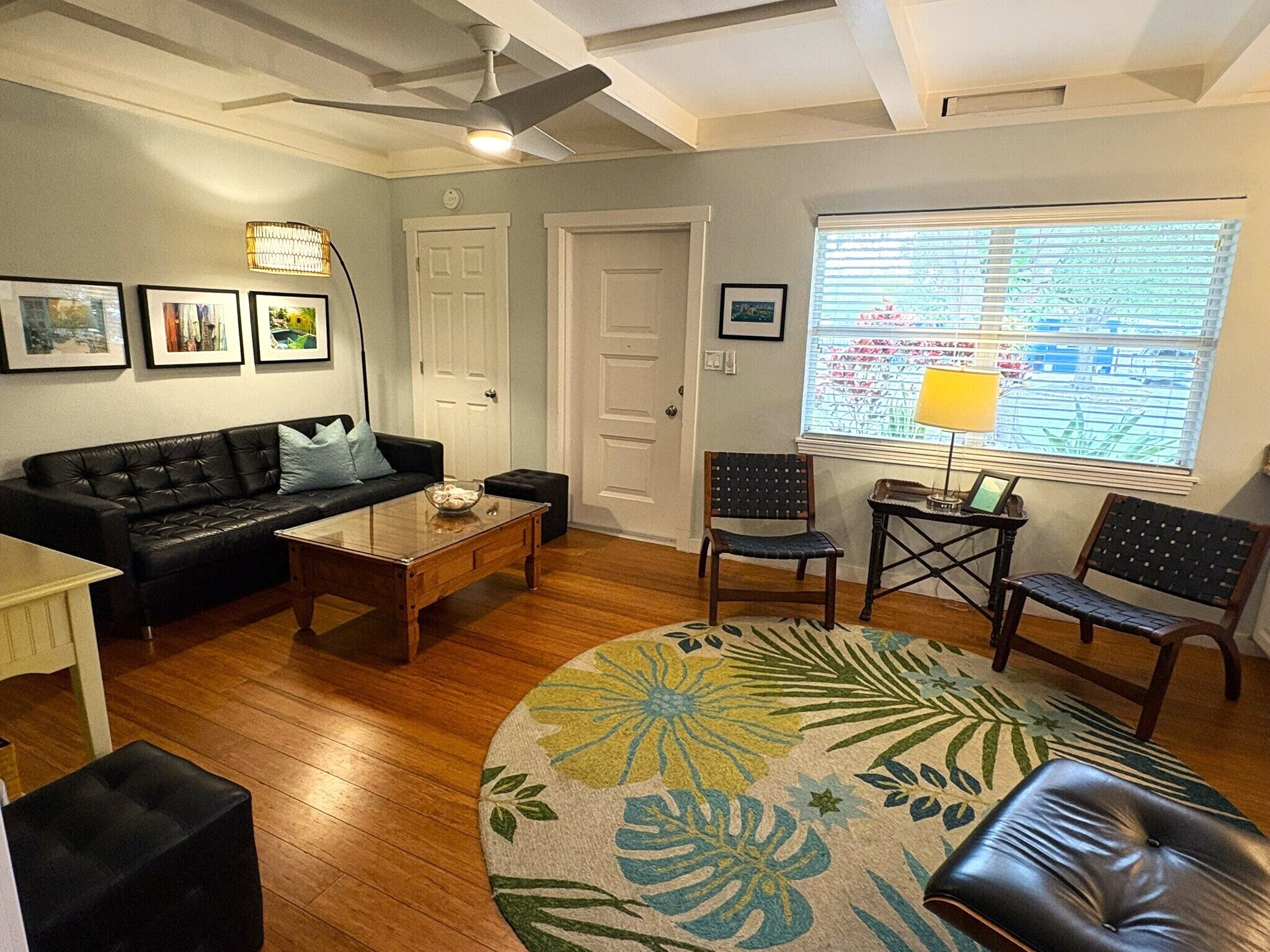A living room with a sofa, coffee table, chairs, a rug, and a window with blinds.