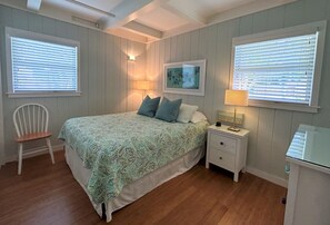 A bedroom with a bed, two bedside tables, a chair, and a window with blinds. - 5 star Quiet, Comfy Home, Pets OK, Walk DTWN, Trolley to Beach ,Bike Legacy Trl (Sarasota)