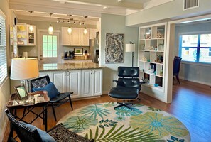 A modern living room with a round coffee table, a black leather chair, and a bookshelf. - 5 star Quiet, Comfy Home, Pets OK, Walk DTWN, Trolley to Beach ,Bike Legacy Trl (Sarasota)