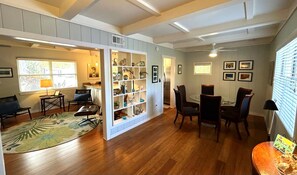 A spacious living room with a wooden floor, a glass dining table, and a built-in bookshelf.