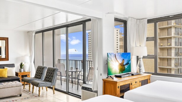 A hotel room with a large balcony, a TV, a bed, and a seating area with chairs. - High Rise Deluxe Ocean View Free Parking/Wifi in Waikiki 3106 (Honolulu)