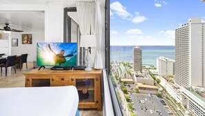 A hotel room with a large TV, wooden desk, and a view of the city and ocean. - High Rise Deluxe Ocean View Free Parking/Wifi in Waikiki 3106 (Honolulu)