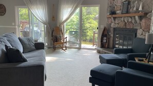 A cozy living room with a stone fireplace, a sofa, and a chair. - Serene Setting on the Platte River (Honor)