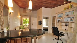 A kitchen with a curved countertop, wooden stools, a black office chair, and a wooden cabinet with glass doors. - Jaco Beach awesome remodeled condo on the main strip. Walk to the beach and town (Jaco)
