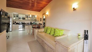 A modern kitchen with stainless steel appliances, a wooden ceiling, and a dining area with a glass table. - Jaco Beach awesome remodeled condo on the main strip. Walk to the beach and town (Jaco)