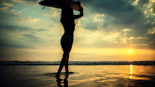 A silhouette of a person holding a surfboard against a sunset backdrop. - Jaco Beach awesome remodeled condo on the main strip. Walk to the beach and town (Jaco)
