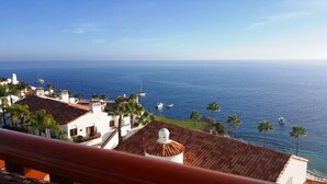 A coastal view with buildings, palm trees, and boats on the water. - MAGNIFICENT OCEAN VIEW Hamilton Cove Condo With Golf Cart Included. (Avalon)