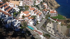 A coastal town with white buildings, a curved swimming pool, and a view of the sea. - MAGNIFICENT OCEAN VIEW Hamilton Cove Condo With Golf Cart Included. (Avalon)