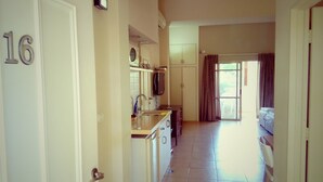 A hotel room with a kitchenette, a bed, and a large window. - Kibbutz Tiratzvi - Country Lodging (Emek HaMaayanot)