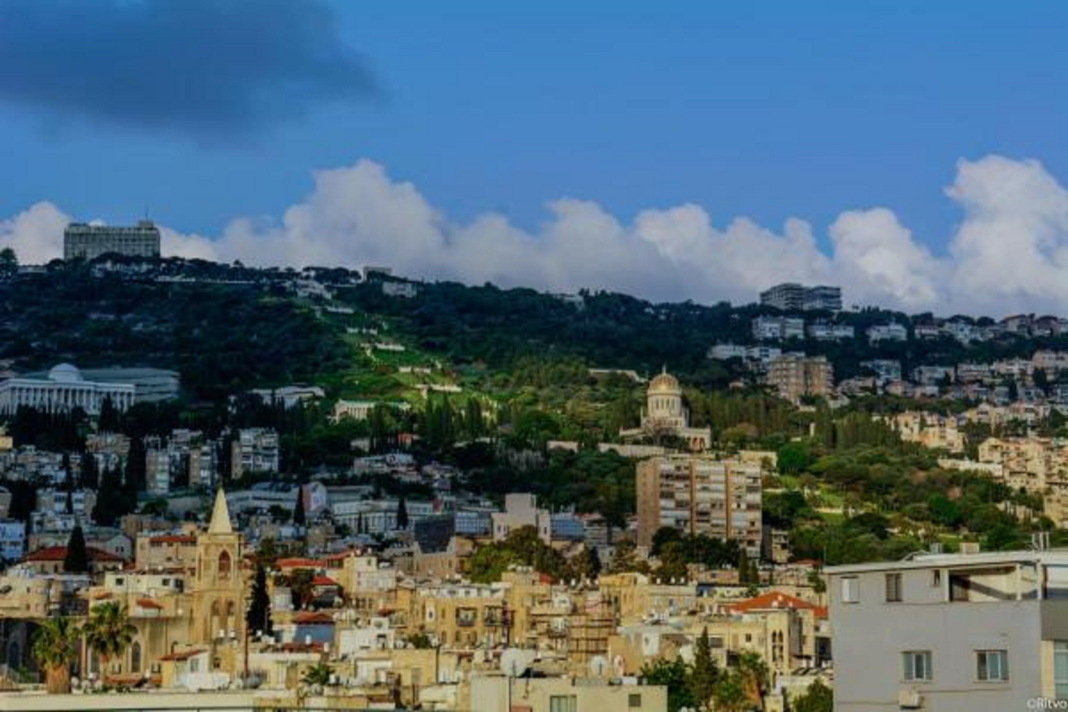 A cityscape with a prominent church, residential buildings, and a hill with scattered structures.