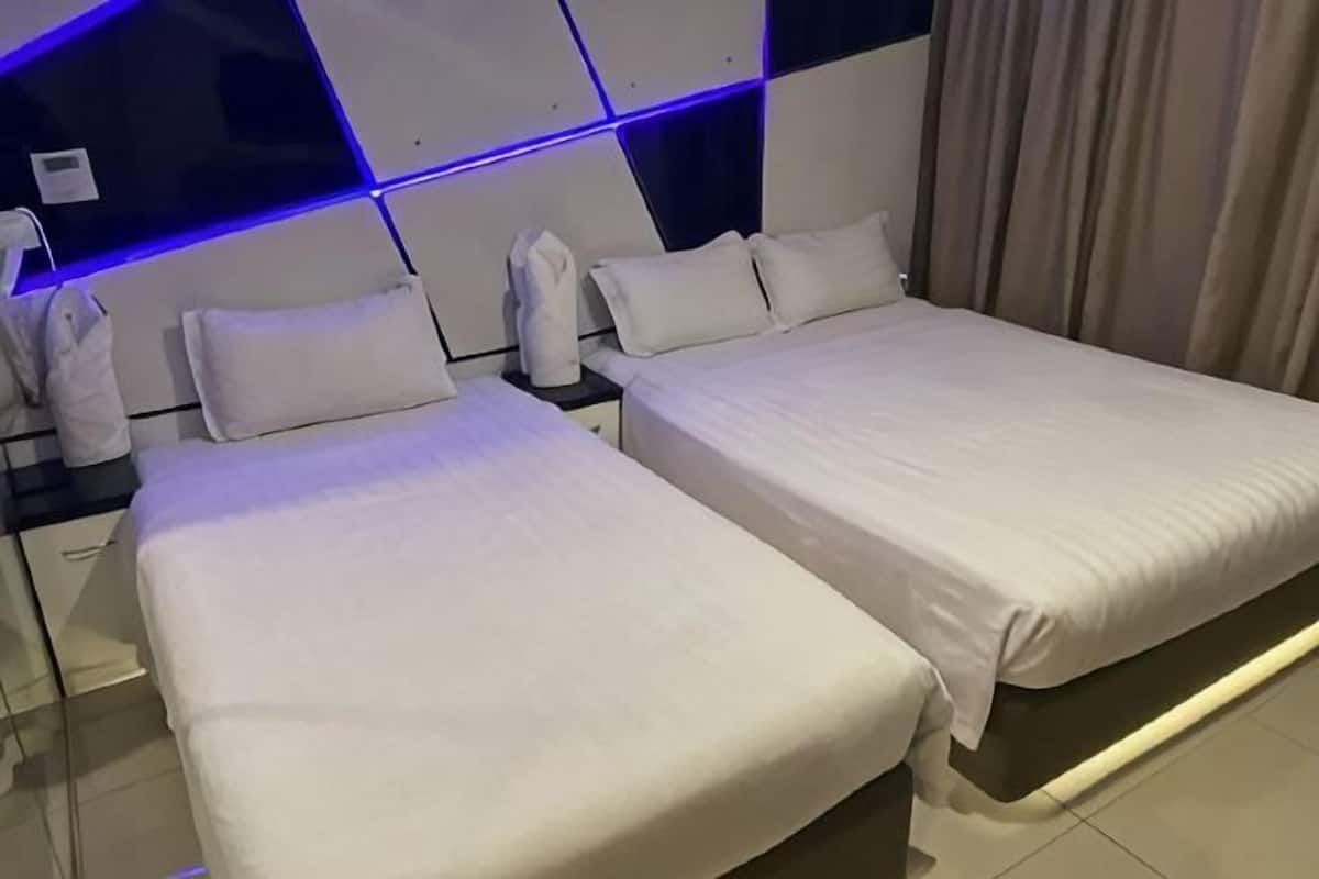 A hotel room with two beds, a modern headboard, and a nightstand with a lamp.