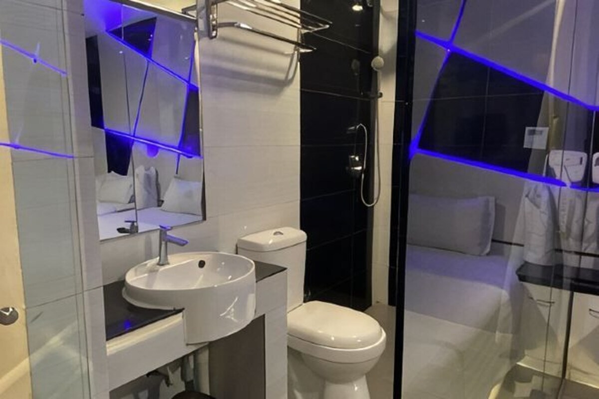 Un baño moderno con cabina de ducha de vidrio, un lavabo blanco y un inodoro.