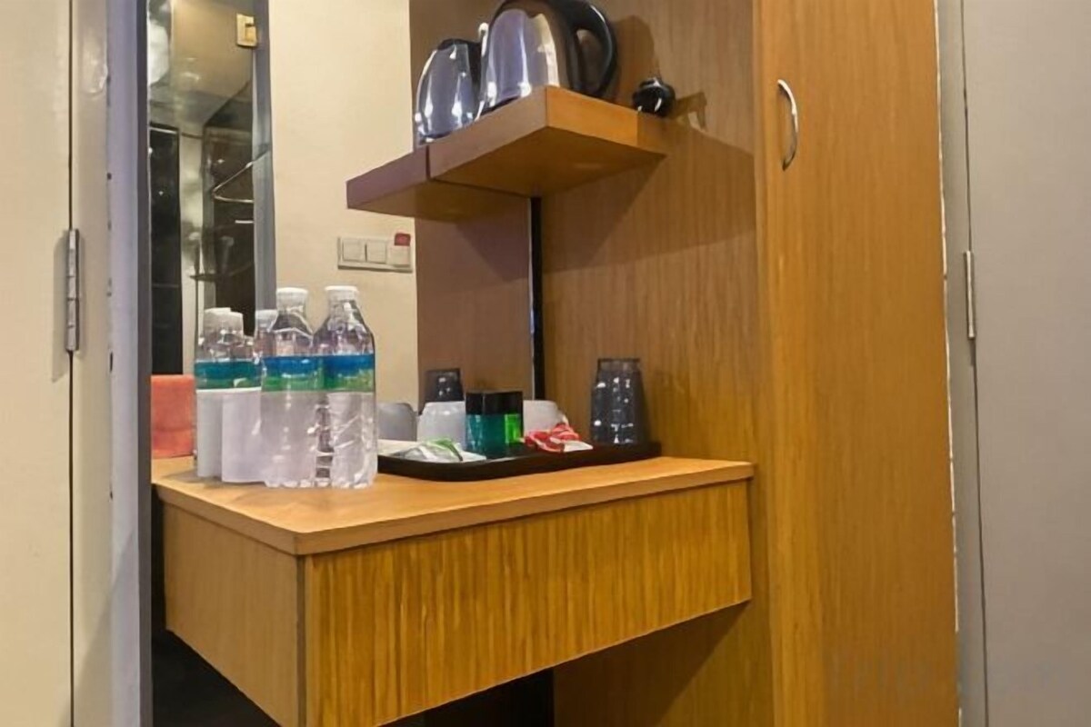 Habitación de hotel con un escritorio de madera, un espejo y un estante con artículos de tocador.