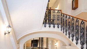 A grand staircase with ornate black railings, a circular glass enclosure, and a wooden finish. - B&B Università (Naples)