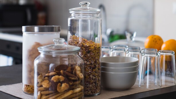 A kitchen counter with glass jars containing various food items, a microwave, and a sink. - B&B Università (Naples)