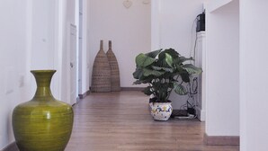 A hallway with a large green vase, a potted plant, and a decorative tile on the wall. - B&B Università (Naples)