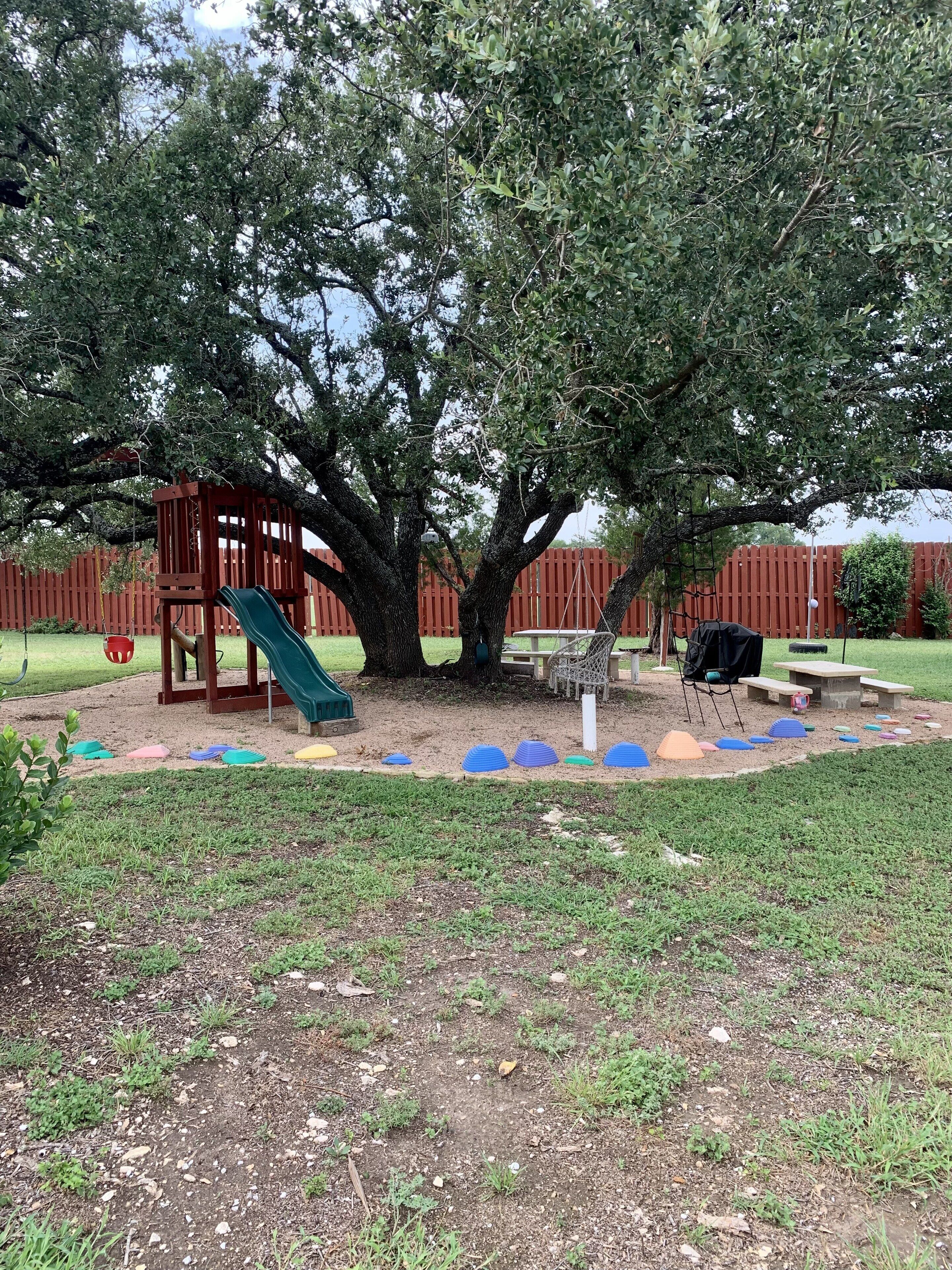 Un parque infantil con un tobogán, estructuras para escalar y una mesa de picnic.