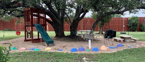 Un parque infantil con un tobogán, estructuras para escalar y una mesa de picnic.