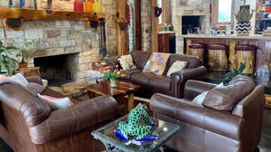 A cozy living room with leather sofas, a fireplace, and rustic decor. - Hudson Bend Casa at Lake Travis Owned by famous chef (Austin)
