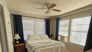A bedroom with a bed, a ceiling fan, a nightstand, a lamp, and a dresser.