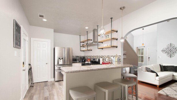 Una cocina moderna con una isla central, electrodomésticos de acero inoxidable y taburetes de bar.