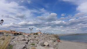 Uma costa rochosa com edifícios ao fundo e céu claro.