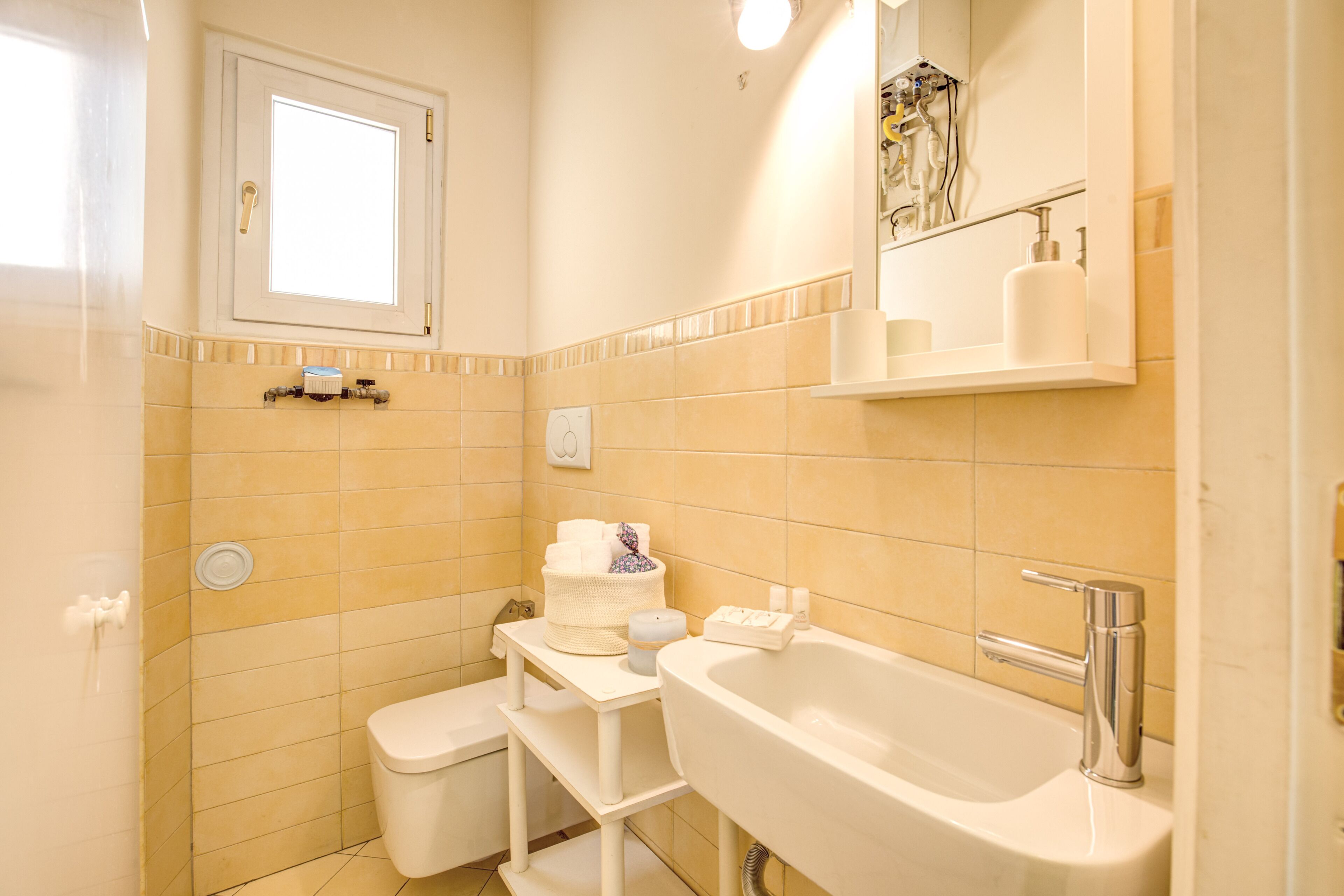 Une salle de bain avec une baignoire, des toilettes et un lavabo. Il y a une fenêtre au-dessus des toilettes et un miroir au-dessus du lavabo.